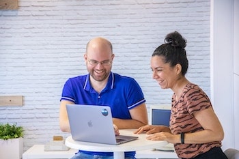 Redsauce employees smiling at the QA tests they do on a laptop