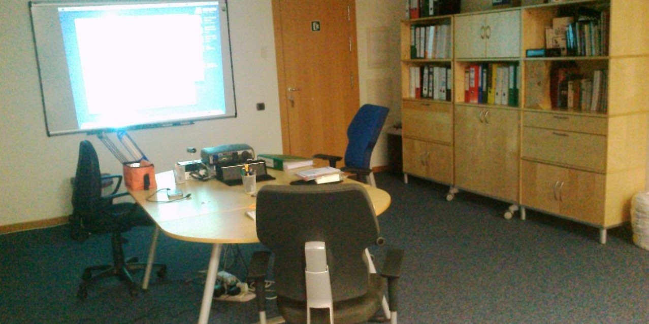 La sala de reuniones de nuestra vieja oficina en Sant cugat, con su cámara iSight, su Mac mini, su proyector y el altavoz Logitech listo para darlo todo. A la derenca, la "base de datos" compuesta pod
